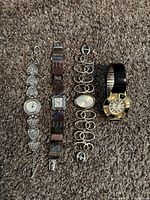 Overhead view of four vintage quartz wristwatches arranged vertically on carpet showing decorative stones and band details.