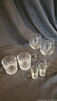 Group of different glass types: 2 crystal highball glasses, 2 shot glasses, and 2 wine glasses shown together on background