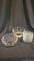 Two large octagonal faceted crystal bowls and six small ribbed clear crystal bowls shown together on a dark backdrop.