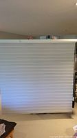 Full view of the off white sheer window blind fully lowered showing alternating opaque and sheer horizontal stripes.