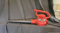 Side view of the Toro electric leaf blower showing the red body with black nozzle and handle.