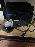 Mastercraft 1/2 inch angle grinder laying on a black surface with carrying bag behind it.