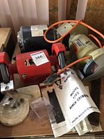 Overview of the set showing Ashland Bench Grinder with paperwork and accessories, Emerson motor behind, and Black & Decker bench grinder to the side.