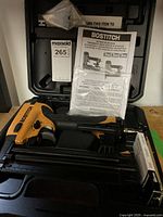Photo showing the Bostitch pneumatic brad nailer and stapler placed inside a plastic carrying case with the manual and price tag visible.