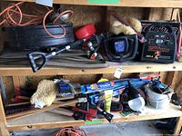 Wide view of shelves showing assorted automotive tools and cleaning accessories including mats, brushes, waxer, booster pack, and extension cords.