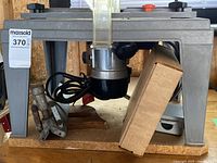 Photo of router mounted on a metal base with power cord, showing general condition and setup.