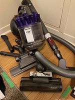 Front view of Dyson DC37 canister vacuum with clear dust bin, purple cyclone assembly, hose and attachments assembled around unit