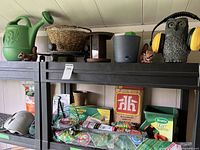 Overview of entire shelving unit showing multiple garden tools and products including watering can, plant basket, seed spreader, and bird feeder
