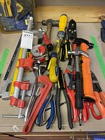 Top view of assorted hand tools including hammers, screwdrivers, clamps, wire cutters, pliers on a workbench.