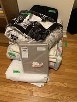 Stack of folded linen items including a sealed King size duvet cover set, single duvet cover, and assorted sheets