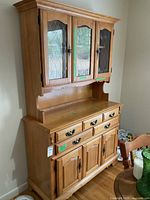 Full view of maple buffet and hutch set showing wood finish, drawers, cabinet doors, and glass door design.