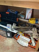 Photo showing assorted electrical items including power strips, connectors, and extension cord among tools and boxes