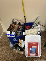 Full view of the painters lot showing roller covers, brushes, extension pole, drop sheets, paint tray, and other accessories in bins and boxes
