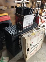 Stacked black resin shelves with slotted surfaces, multiple pieces shown.