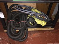 Photo showing black corrugated tubing and various hoses bundled together underneath a piece of furniture.