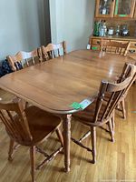 Maple kitchen table with 6 matching chairs arranged around it, showing the wood finish and style.