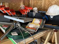 View of two black plastic tackle style tool boxes with open extendable trays filled with various tools and hardware items, white hard hat, and two packages of hook and loop straps.
