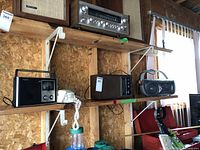 Three radios on wooden shelves including a Sony radio with wood grain finish and two Panasonic radios, one with black casing and one with silver knobs.