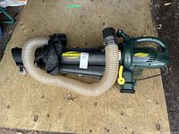 Side view of Yardworks electric blower/vac with attached hose and leaf collection bag on wooden surface.