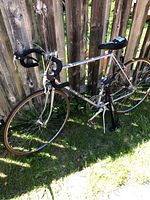 Full side view of VeloSport road bike leaning against wooden fence on grass.