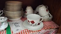 Stack of 9 bowls and 10 nappies with 5 teacups and 9 saucers, displaying the red rose design on white porcelain.