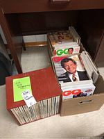 Three boxes containing GQ magazines: one red binder box and two cardboard boxes of loose issues.