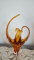 Side view of amber glass centrepiece showing tall curved spout and clear base.