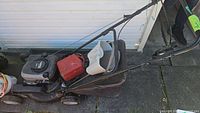 Full side view of Murray lawn mower showing engine, gas container, grass catcher bag, white head protector.