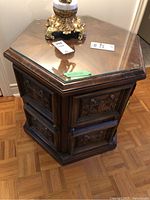 Full view of octagonal wooden table with clear glass top and base showing carved wood panels.