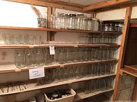 Wide view of multiple shelves filled with clear glass preserving jars and some lids.