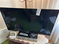 Front and angled views of RCA 38-inch TV, Philips DVD VCR player underneath the TV, two remote controls on top of VCR, and four VHS tapes stacked beside them.