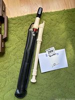 Two recorders laid out next to a note card and a black case on green carpeted floor