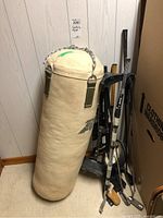 Full view of heavy punching bag and golf clubs leaning against wall.