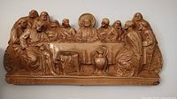 Ceramic wall art featuring a relief depiction of The Last Supper with Jesus and twelve apostles at a table, warm brown tone.