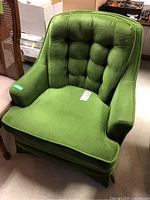 Front and angled view showing the overall shape, upholstery fabric, button tufting and cushion of the chair.