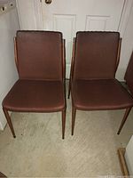 Two brown vinyl vintage dinette chairs with metal frames, showing wear and rust on legs.