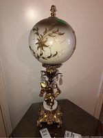 Full view of the vintage table lamp showing the white glass shade with gold floral design and ornate gold-tone base with crystal accents, measuring 29 inches in height.