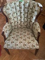 Front view of the smaller ladies wing chair showing floral upholstered fabric and mahogany frame curving around the arms and backrest.