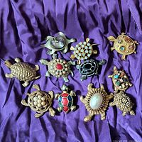 Overview photo showing all 10 turtle pins arranged on a purple fabric background.