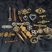 Overhead photo displaying entire collection of 23 assorted scatter pins in various metal tones and decorated with colored stones and intricate designs