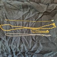 Four gold-filled pieces including 20-inch chain, bracelet with charm, 18-inch white gold tone chain, and chain with pendant.