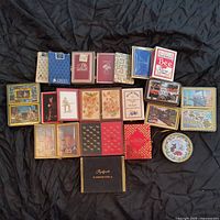 Full lot of assorted playing card decks arranged on black fabric, showing a variety of boxes, tins, and deck styles including airline promotional and souvenir themes.