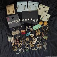 Overview of all earrings, laid flat on black cloth, showing multiple pairs of various styles and brands including Belk Silverworks, Lauren Ralph Lauren, and KR by Hattiebu