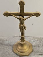 Full view of solid brass crucifix with cross and figure of Jesus Christ on a rounded base, 22 inches tall.
