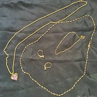 All four gold jewelry pieces displayed on black fabric background