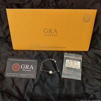GRA certification card, silver bracelet with center stone, and clear bag with stone label.