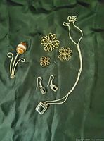 Sterling silver jewelry pieces arranged on black fabric including brooch, scatter pins, necklace, and earrings