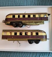 Top side view of two articulated rail car sections showing maroon and cream paint with window openings