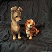 Both Lady and the Tramp ceramic figurines displayed on black fabric, showing size and condition