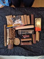 Top-down photo showing wooden railroad building pieces, a small plastic bag with wheels, and various rectangular wood pieces on a black blanket.
